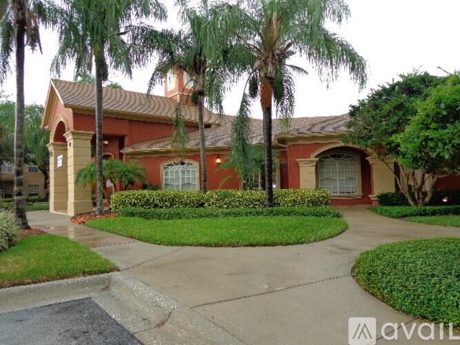 A house with a red roof and palm trees in front.