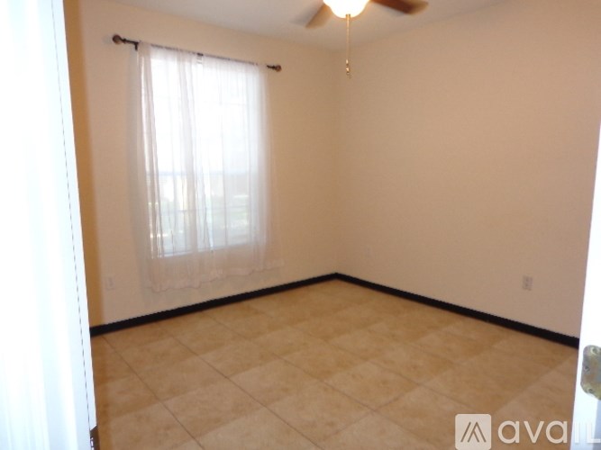A room with a ceiling fan and a window with curtains.