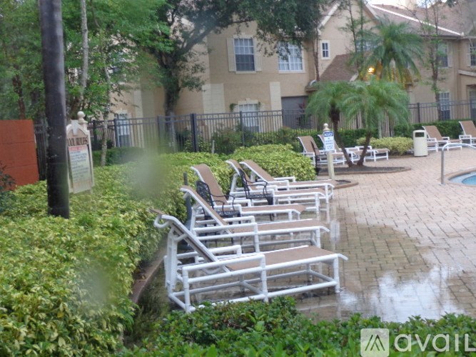 A poolside area with chairs and a fence in the background.
