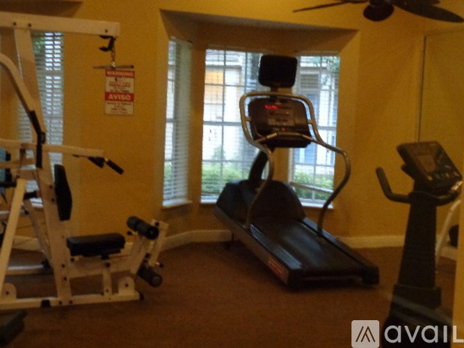 A gym room with a treadmill, weights, and a fan.