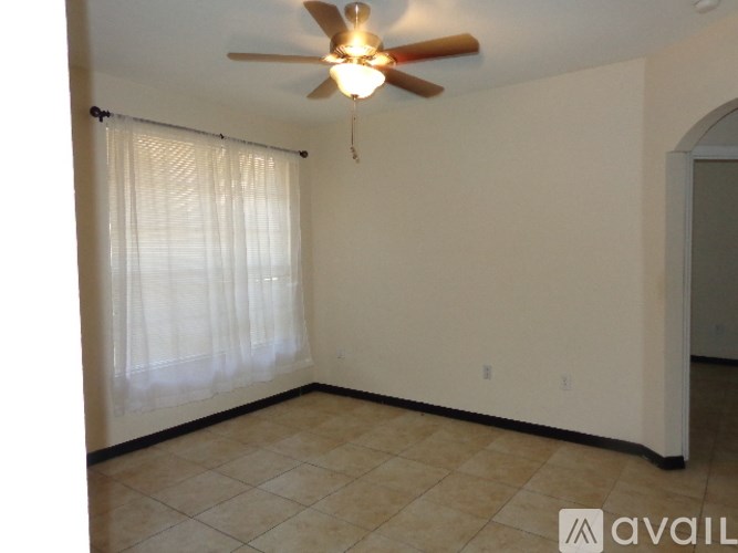 A room with a ceiling fan and a window with curtains.