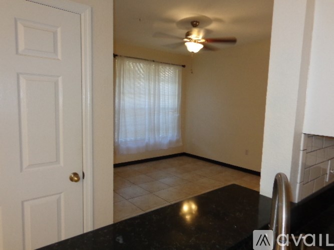 A room with a ceiling fan and a door.