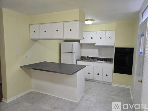 A kitchen with white cabinets and a grey countertop.