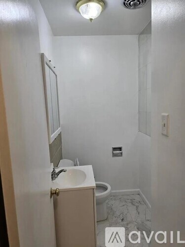 A bathroom with a toilet, sink, and mirror.