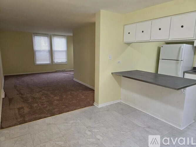 A kitchen area with a refrigerator, cabinets, and a countertop.