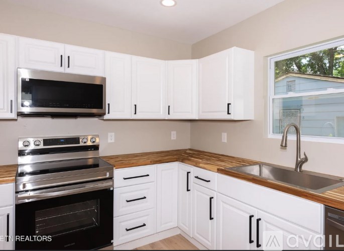 A kitchen with white cabinets and a wooden countertop.