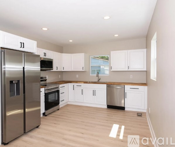 A kitchen with white cabinets and a wooden floor.