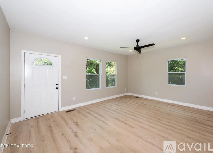 A spacious room with a ceiling fan and wooden flooring.