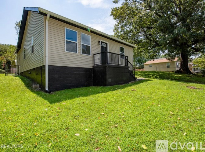 A small house with a balcony is surrounded by a grassy area.