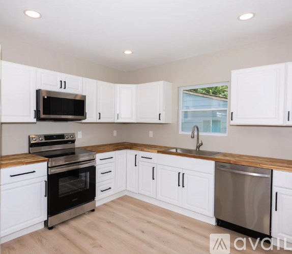 A kitchen with white cabinets and a wooden countertop.