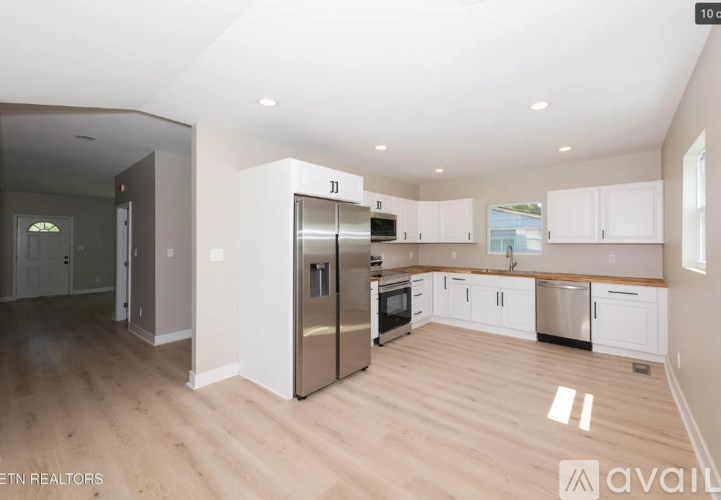A spacious kitchen with white cabinets and a wooden countertop.