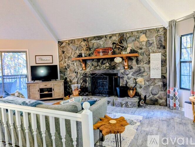 A living room with a stone fireplace and a television.