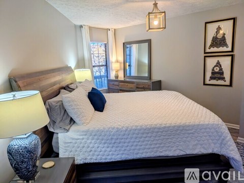 A bedroom with a large bed and a dresser with a mirror above it.