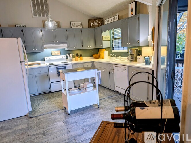 A kitchen with a white fridge and a white island with a basket of fruit on it.