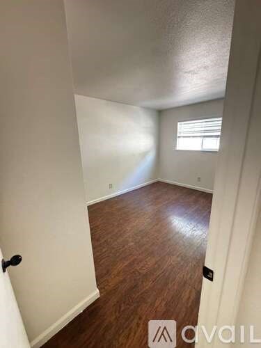 A room with wooden flooring and white walls.