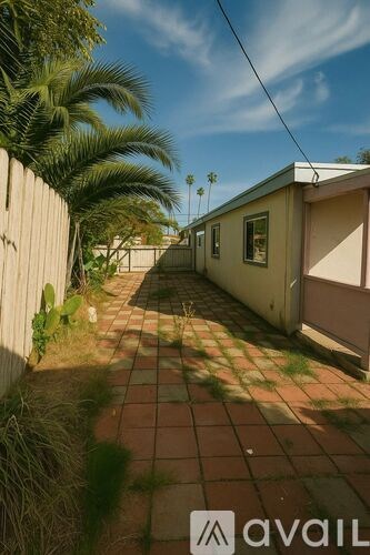 A sunny day in a backyard with a tiled floor and a wooden fence.