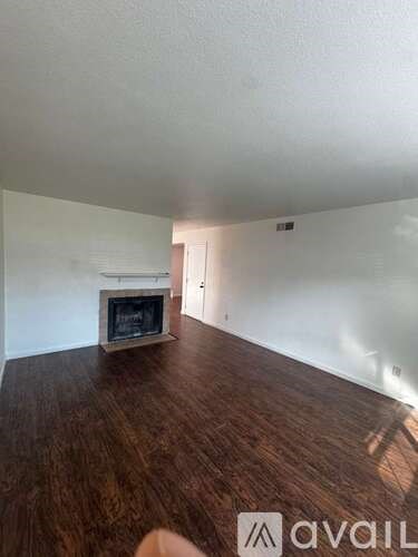 A living room with a fireplace and wood flooring.