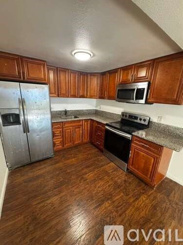 A kitchen with wooden cabinets and a stainless steel refrigerator.
