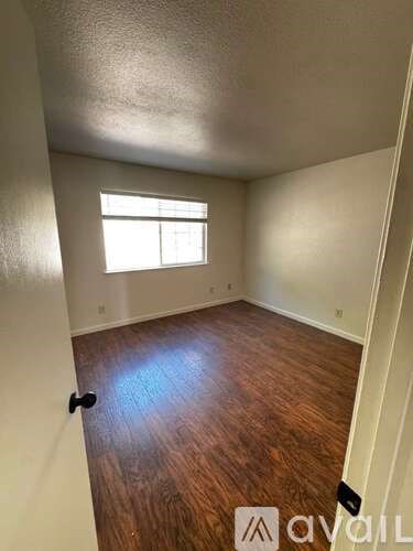 A room with wooden flooring and a window letting in light.