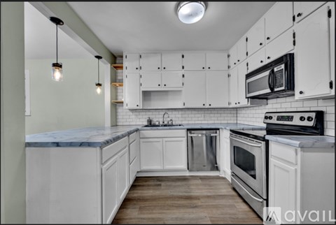 A kitchen with white cabinets and a marble countertop.