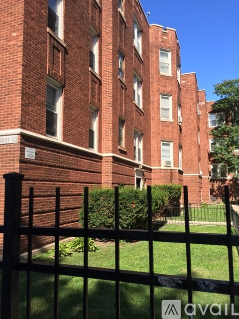 A tall red brick building with a black fence in front.