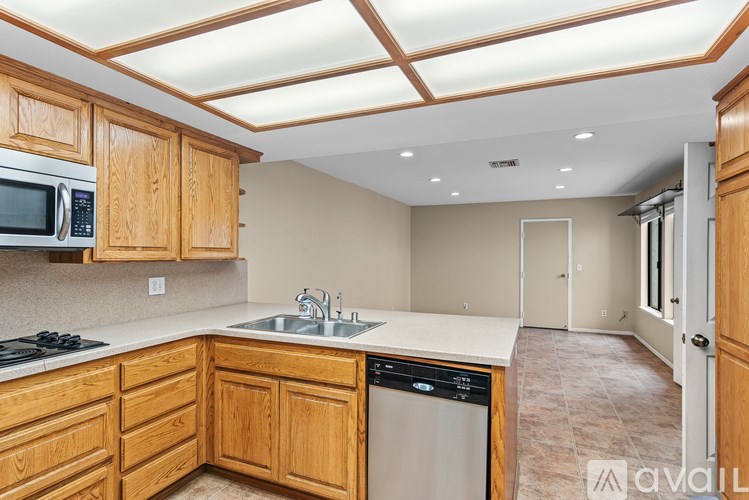 A kitchen with wooden cabinets and a stainless steel dishwasher.