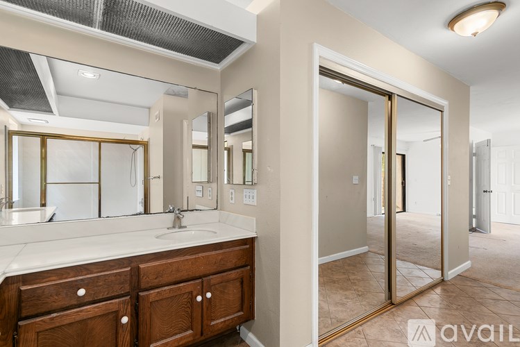 A bathroom with a sink, mirror, and wooden cabinets.