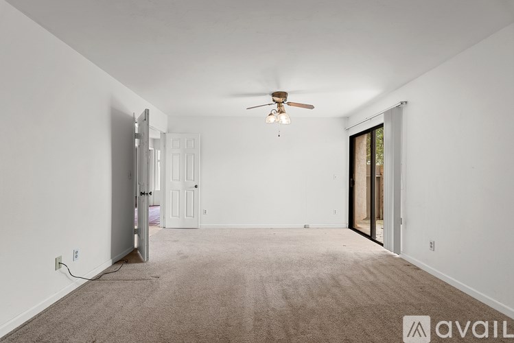 A spacious room with a ceiling fan and carpeted floor.