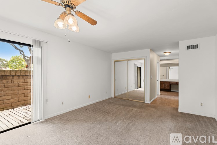 A spacious room with a ceiling fan and carpeted floor.