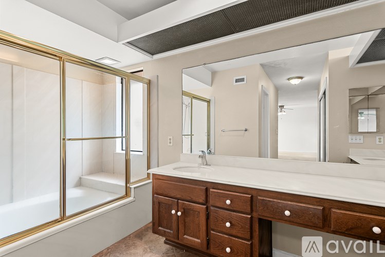 A bathroom with a vanity, mirror, and shower.