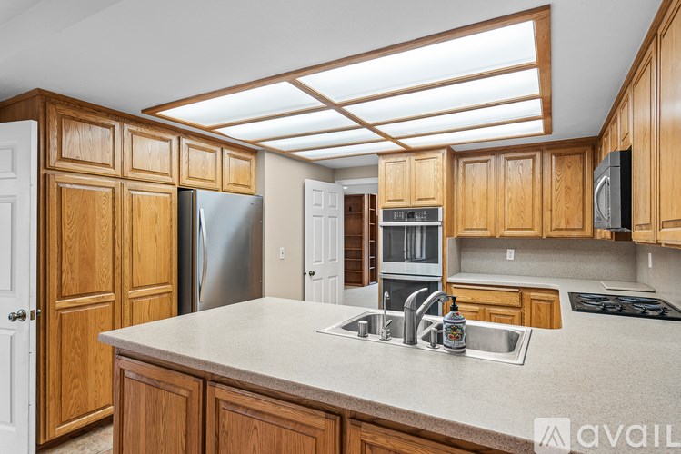 A kitchen with wooden cabinets and a stainless steel refrigerator.