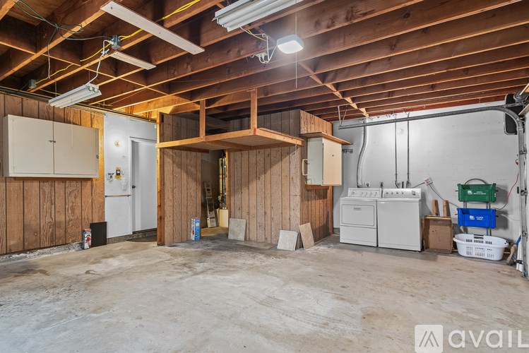 A large empty room with wooden walls and ceiling, and a white door in the left side.