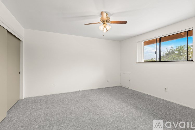 A room with a ceiling fan and a window overlooking the outdoors.