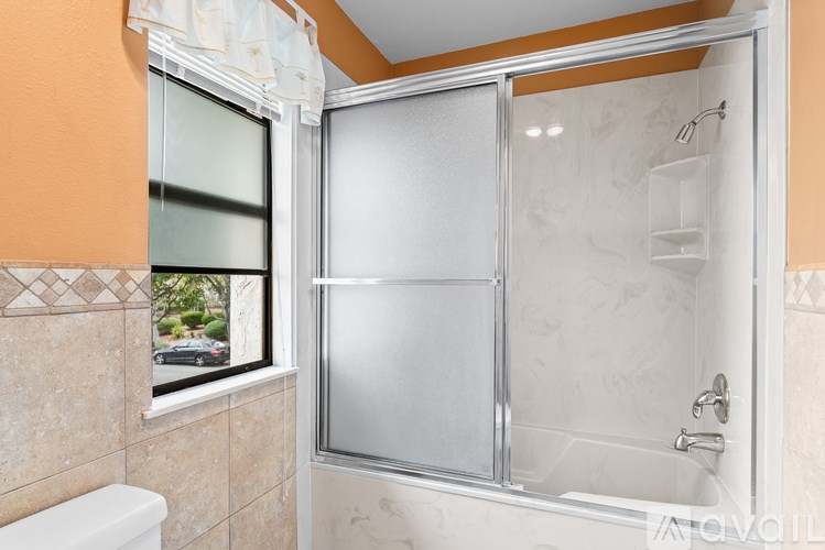 A bathroom with a glass shower door and a window.