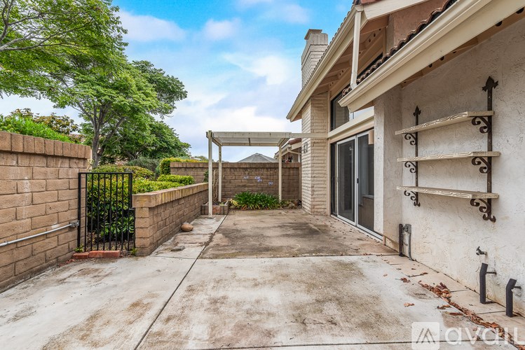 A concrete driveway leads to a house with a black gate on the left.