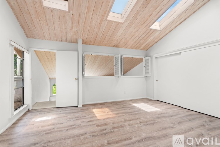 A spacious room with wooden floors and a skylight.