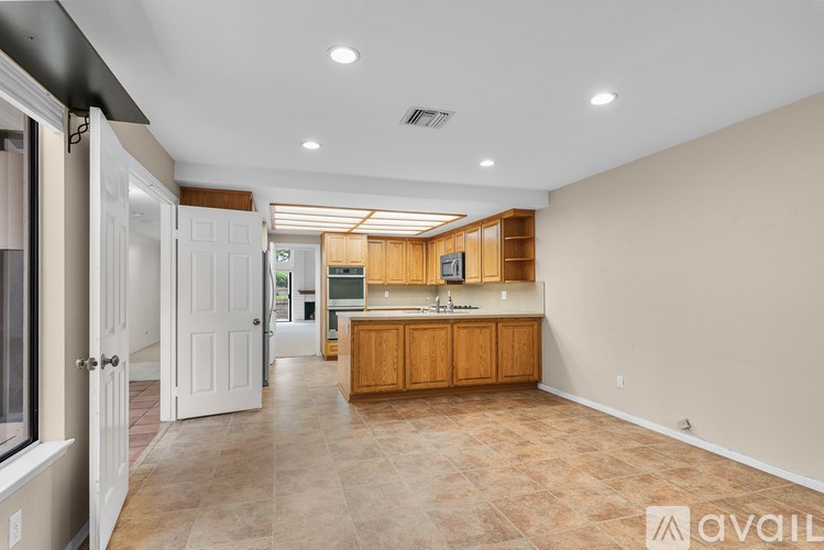 A kitchen with wooden cabinets and a countertop is available for rent.