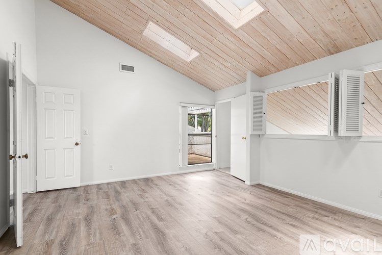 A spacious room with wooden floors and a skylight.