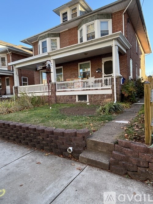A brick house with a white porch and a wooden fence.
