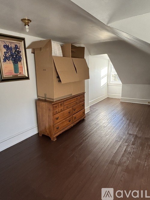 A room with a wooden floor and a dresser with boxes on top of it.