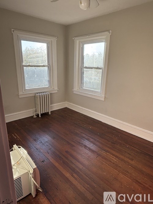 A room with wood floors and two windows.