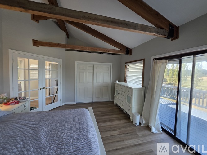 A bedroom with a large bed and a balcony overlooking the ocean.