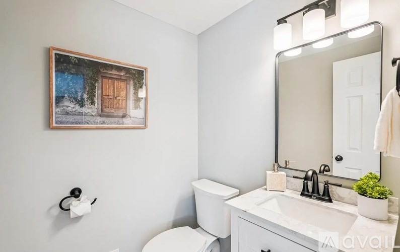 A bathroom with a toilet, sink, and a mirror.