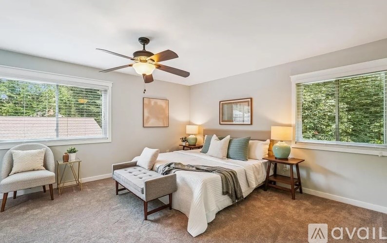 A bedroom with a large bed, a chair, and a ceiling fan.