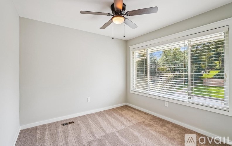 A room with a ceiling fan and a window with blinds.