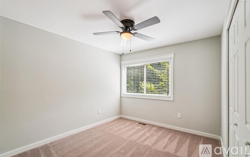 A room with a ceiling fan and a window with blinds.