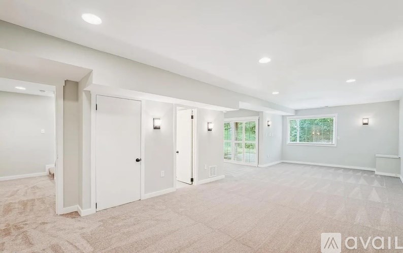 A spacious room with white walls and carpeted floor.