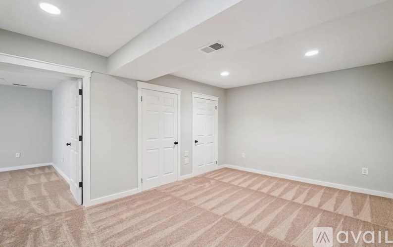 A room with carpeted flooring and two doors.