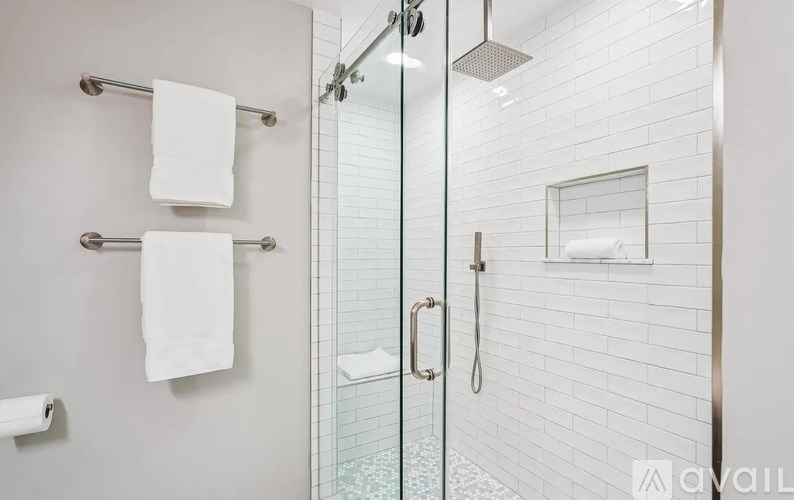 A white bathroom with a glass shower door and towel racks.