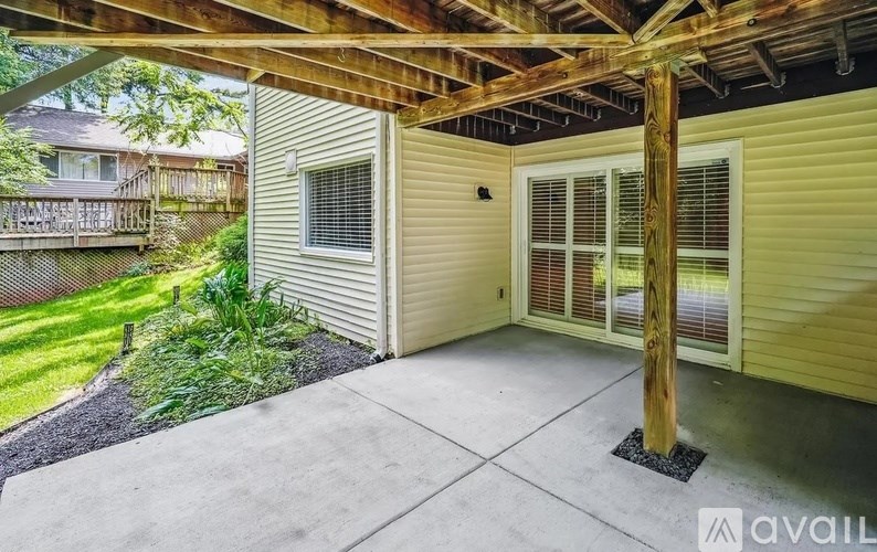 A patio area with a wooden pergola and sliding glass doors.